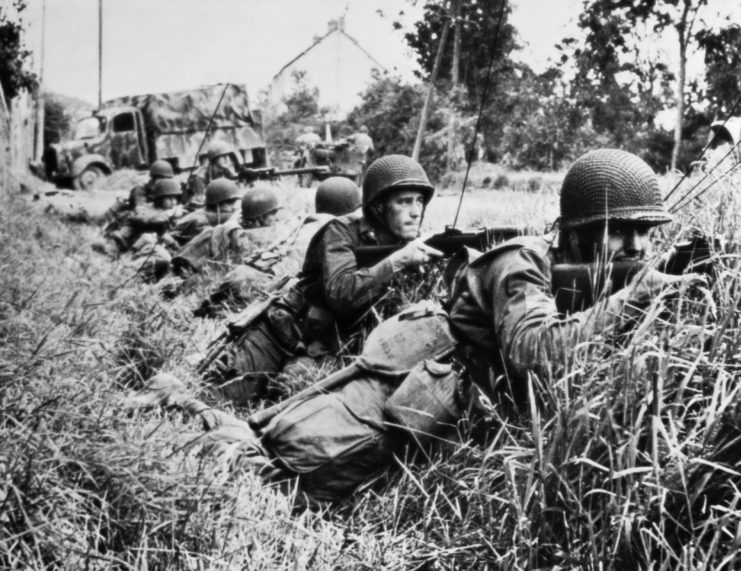US soldiers aiming their weapons from a grassy ditch