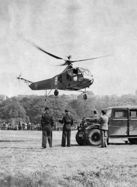 Sikorsky R-4B "Hoverfly" hovering over the ground while three men watch