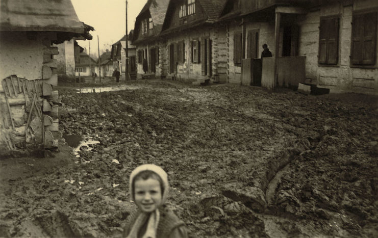 Child standing in the middle of a muddy street in a Russian village