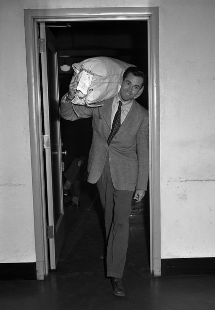 Henry Fonda carrying a duffel bag on his shoulder