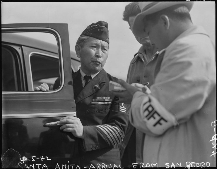 Japanese-American veteran being led into a vehicle by two men