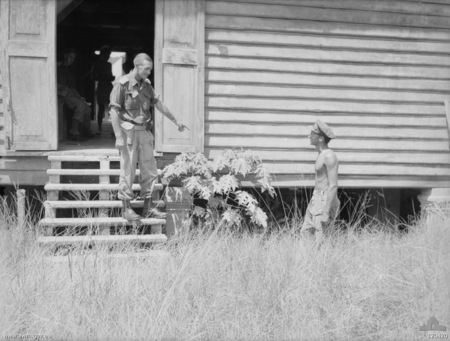 Jock McLaren pointing at the bottom of a hut while standing with another officer