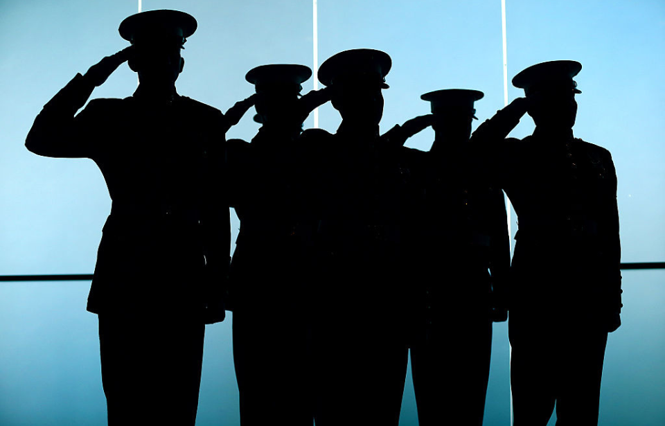 Five US Marines saluting while in silhouette