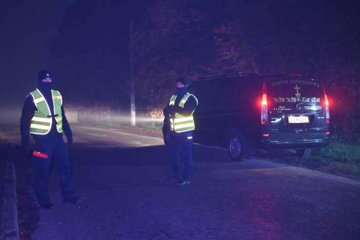 Two Polish police officers blocking off a road at night
