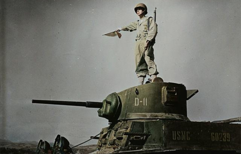 US Marine Corps signalman standing atop an M3 Stuart