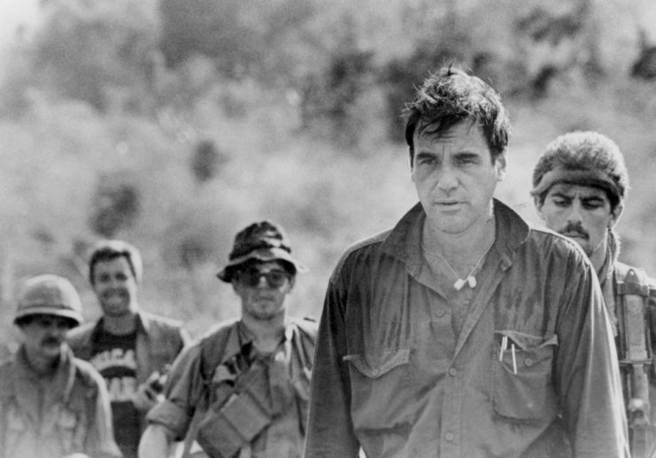 Oliver Stone standing with cast members on the set of 'Platoon'