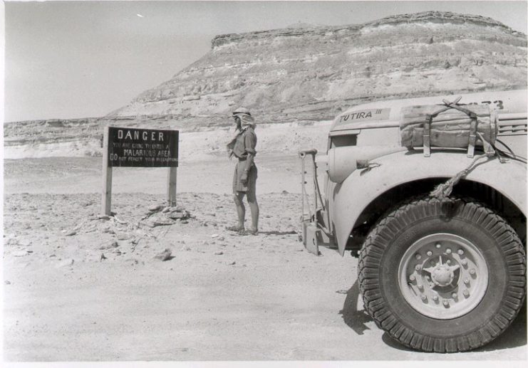 Soldier reading a "DANGER" sign in the desert