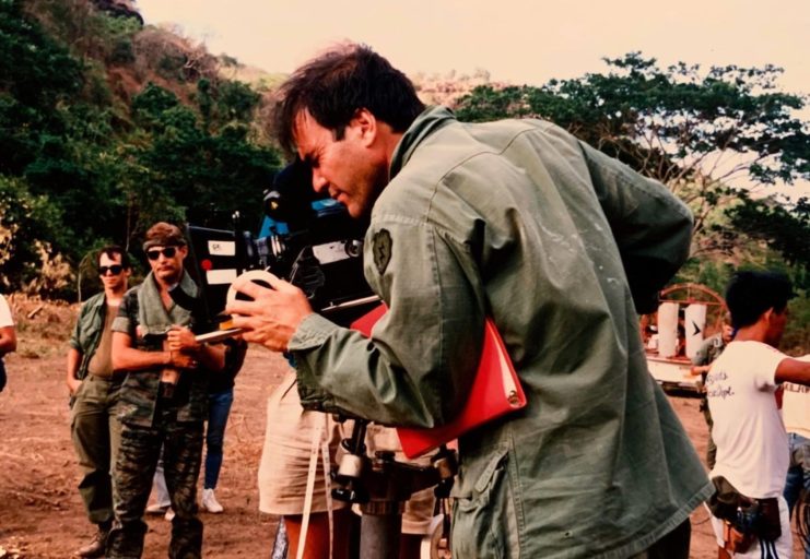 Oliver Stone looking into a movie camera