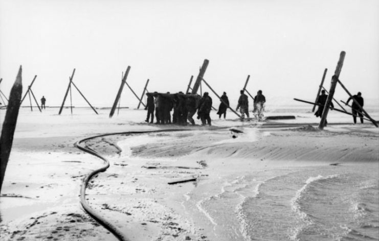 German soldiers sticking wooden poles into sand