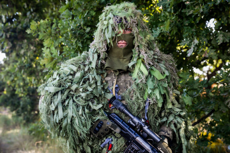 Disguised Ukrainian sniper holding his rifle