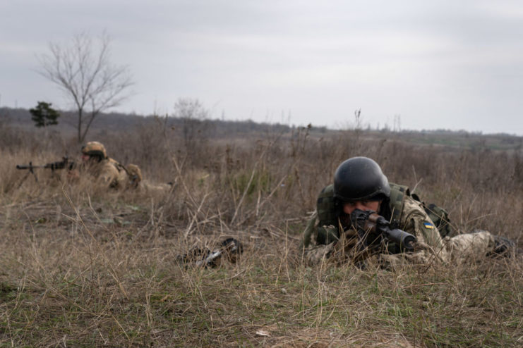 Ukrainian soldier aiming his rifle while lying on the ground