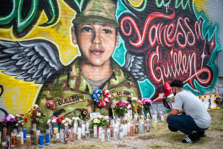 Man crouching in front of a memorial to Vanessa Guillén