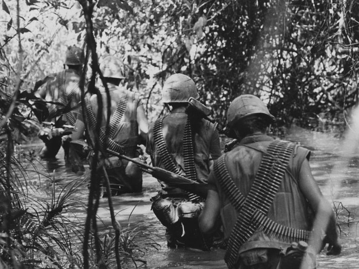 Five members of Company F, 2nd Battalion, 5th Regiment wading through a waist-deep stream