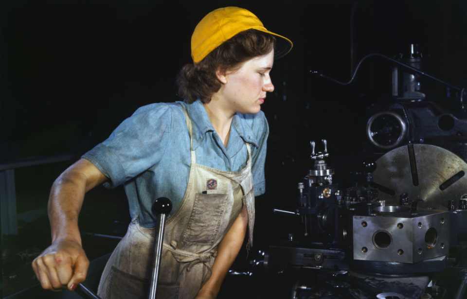 Female operating a machine along a factory assembly line