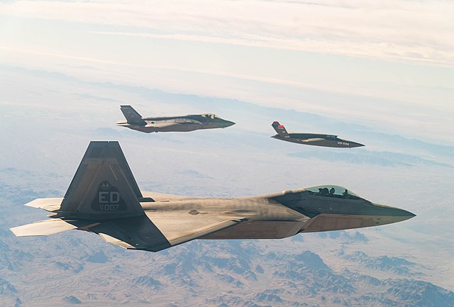 Lockheed Martin F-35 Lightning II and F-22 Raptor flying alongside a Kratos XQ-58A Valkyrie
