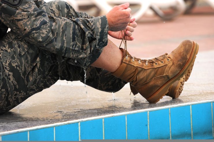 Airman tying their boots by the edge of a pool