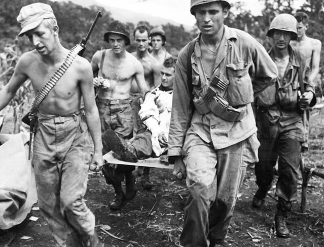 Members of the 511th Parachute Infantry Regiment, 11th Airborne Division carrying an injured comrade on a stretcher