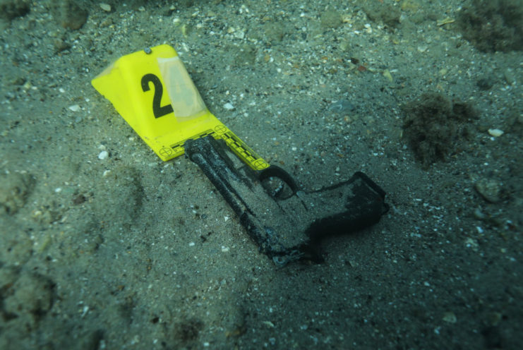 Gun lying on the ocean floor with a police evidence tag beside it