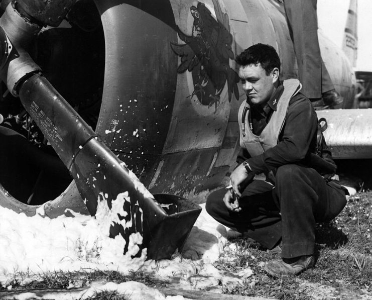 Lt. Charles Easey kneeling beside the damage propeller of his Republic P-47 Thunderbolt