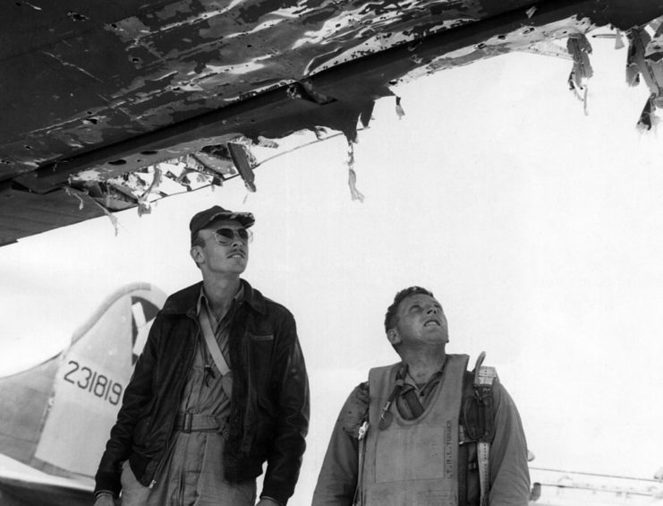 Two airmen staring at the damaged under-section of a Boeing B-17 Flying Fortress
