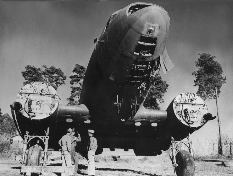 Ground crews standing below a Douglas C-47 Skytrain missing a number of parts