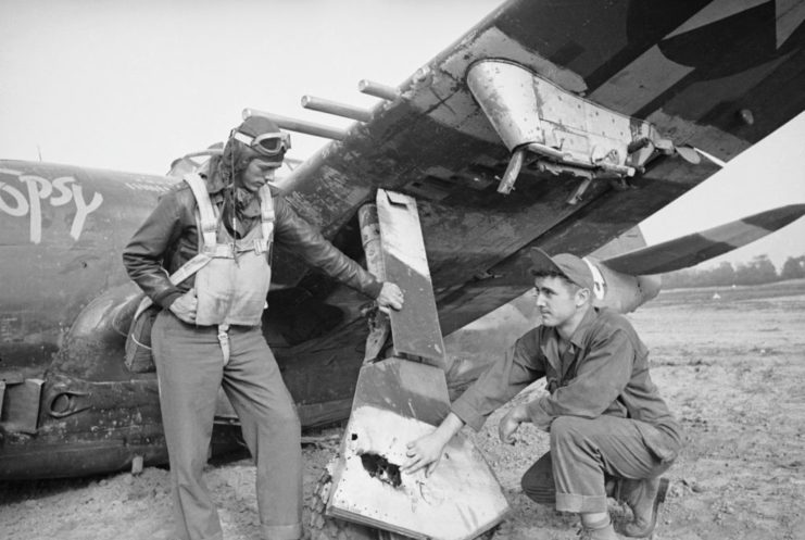 Lt. Quentin Aanenson and another airmen look at the damaged undercarriage of his Republic P-47 Thunderbolt