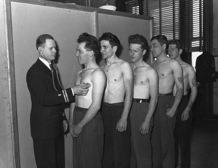 The Sullivan brothers lined up shirtless in front of a military doctor