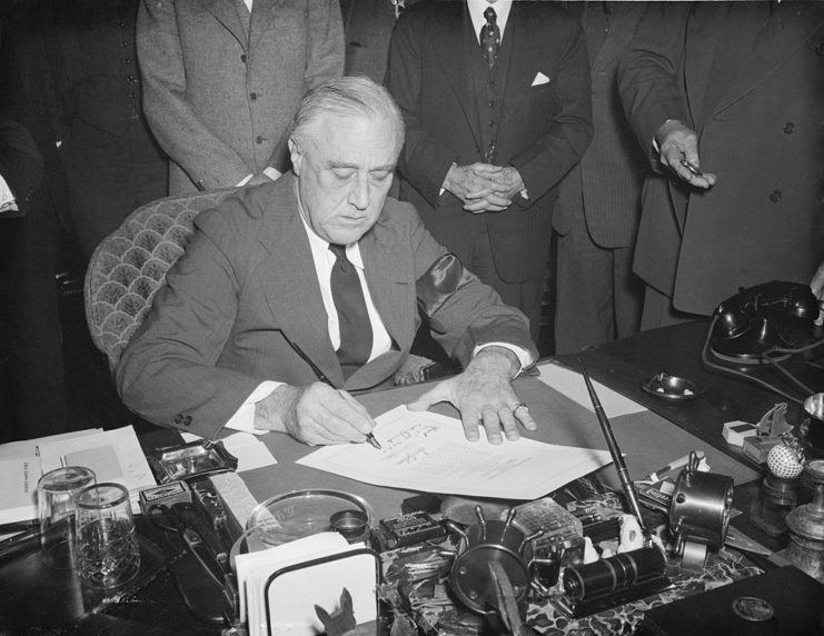 Franklin D. Roosevelt signing the declaration of war against Japan at his desk