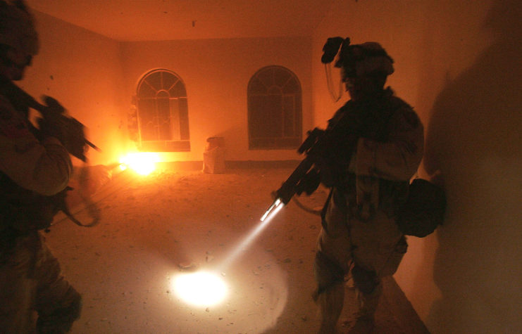 Two US soldiers standing in a dimly-lit room