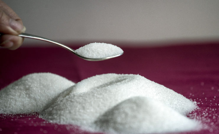 Teaspoon of sugar held over a larger pile