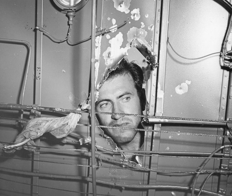 Lt. Louis Zamperini looking through a large hole in his damaged aircraft