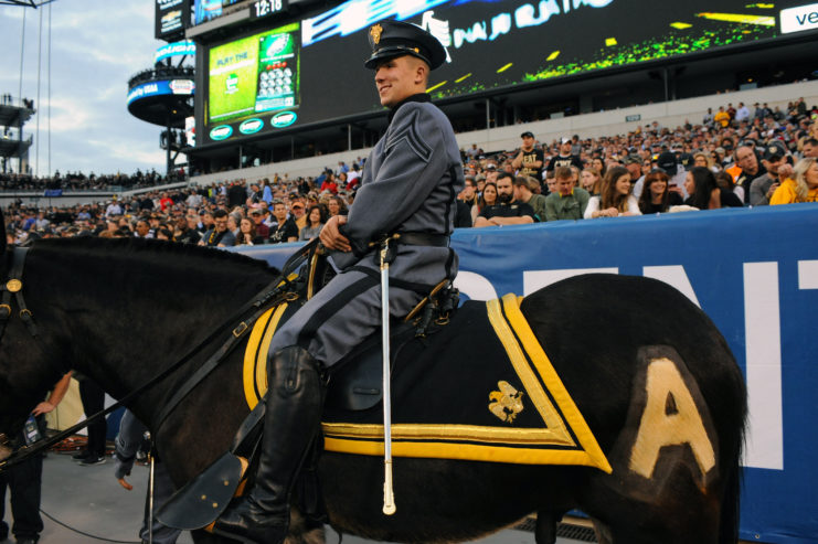Cadet riding the Army Mule Ranger at a packed football stadium