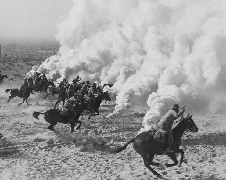 Cavalrymen charging forward through smoke grenades