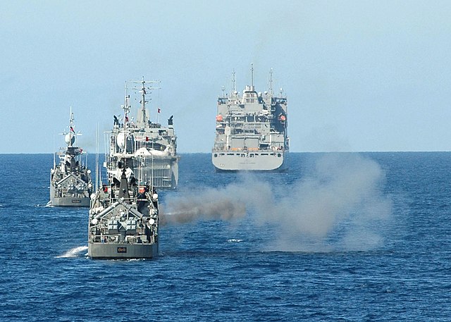 HTMS Sukhothai (FS-442) firing at a target while three ships sail behind her