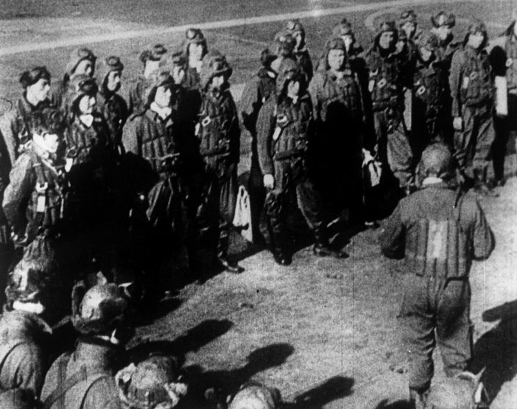 Japanese pilots standing around a superior on the deck of an aircraft carrier