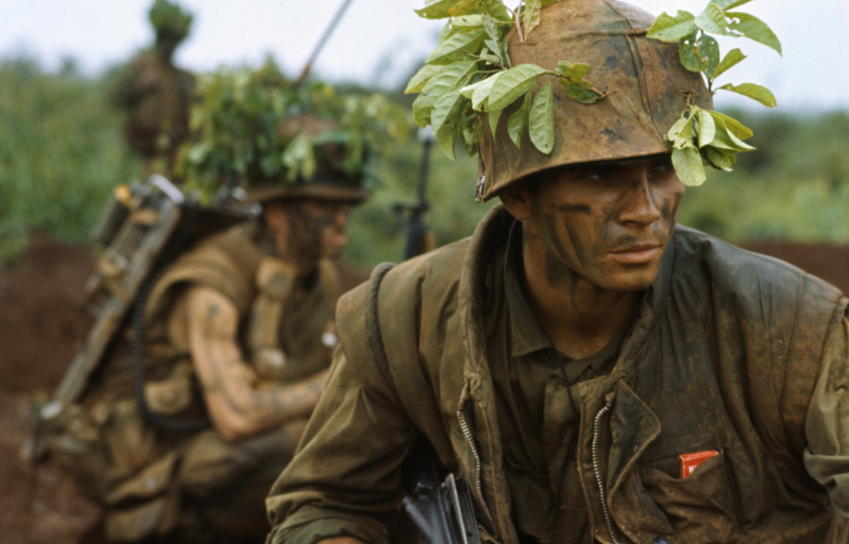 Three camouflaged soldiers squatting in bushes