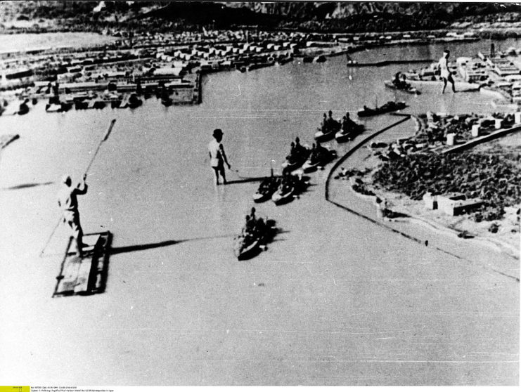 Three Japanese military personnel standing in a model of Pearl Harbor