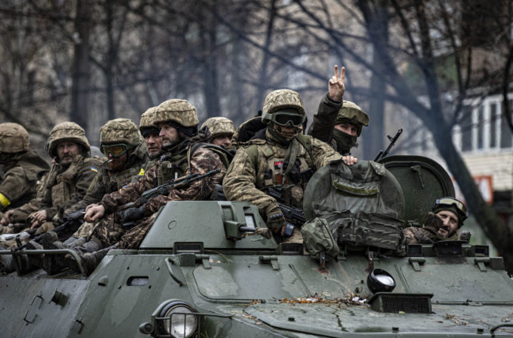 Ukrainian soldiers sitting on top of a tank