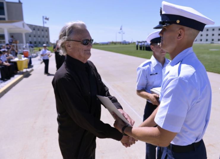 Kris Kristofferson handing a graduation certificate to his son, Jesse Kristofferson