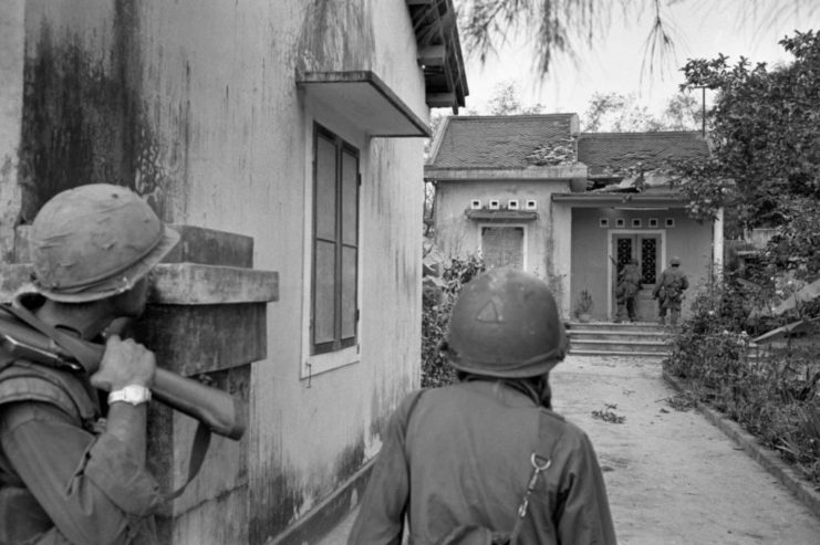US Marines walking along the side of a house