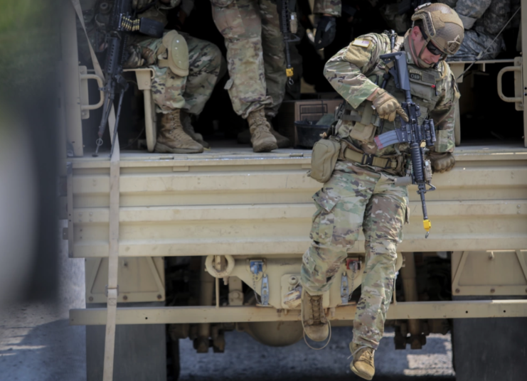 Members of Charlie Company, 1st Squadron, 102nd Cavalry Regiment, New Jersey Army National Guard jumping out of the back of a military vehicle