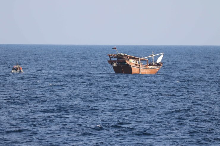 Boarding team from the USS Chinook (PC-9) sailing toward a rusty fishing vessel