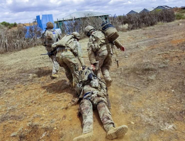 Three members of Charlie Troop, 1st Squadron, 102nd Cavalry Regiment, New Jersey Army National Guard pulling an injured comrade to safety