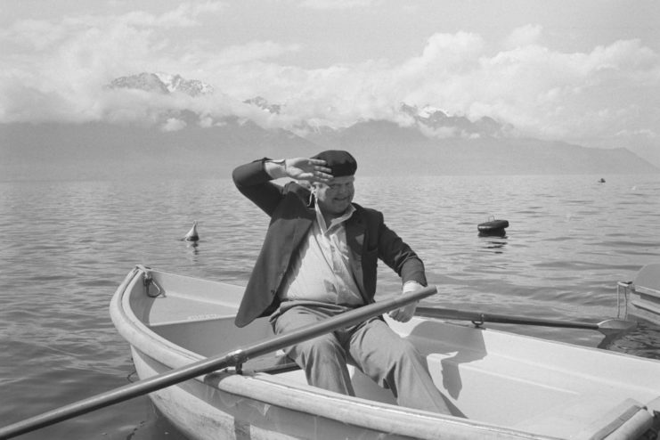 Benny Hill saluting while sitting in a rowboat