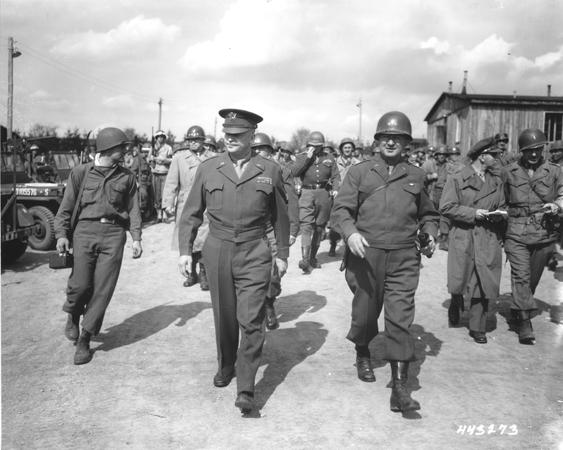 Dwight D. Eisenhower and Troy Middleton walking with a group of military officers through Ohrdruf concentration camp