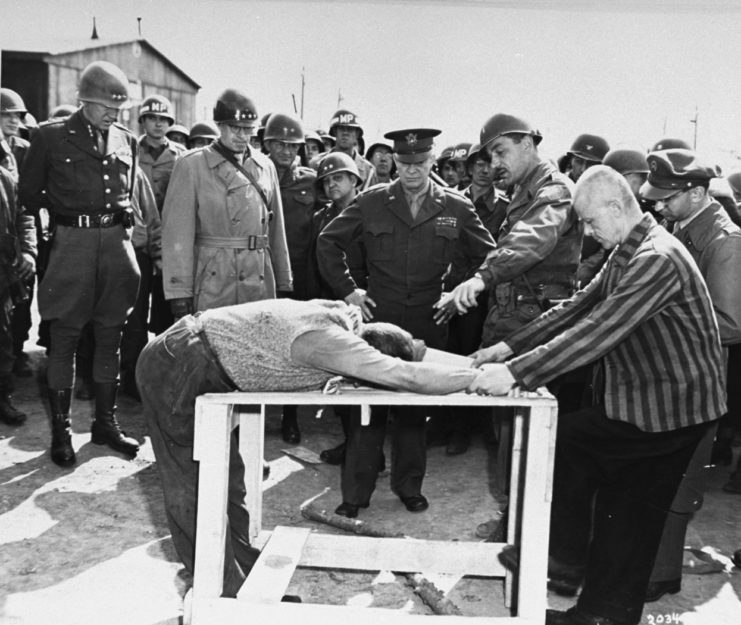 Dwight D. Eisenhower, George Patton and other military officers watching survivors of Ohrdruf concentration camp demonstrate torture methods