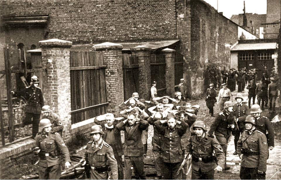 German soldiers leading prisoners along the side of a building