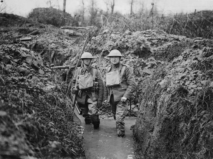 Two British soldiers standing in a partially-flooded trench