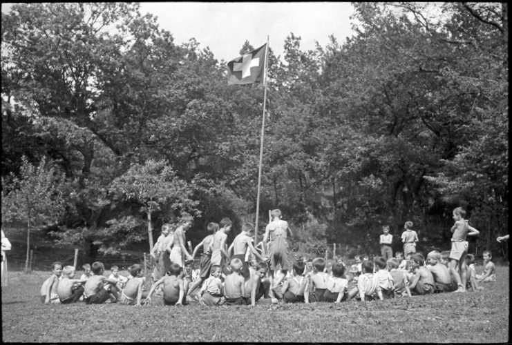 Serbian refugees sitting around a Swiss flag