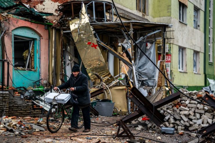 Man pushing his bicycle down a street covered in rubble